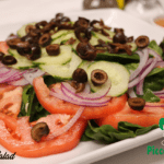 a plate of green salad by Piccola Italia